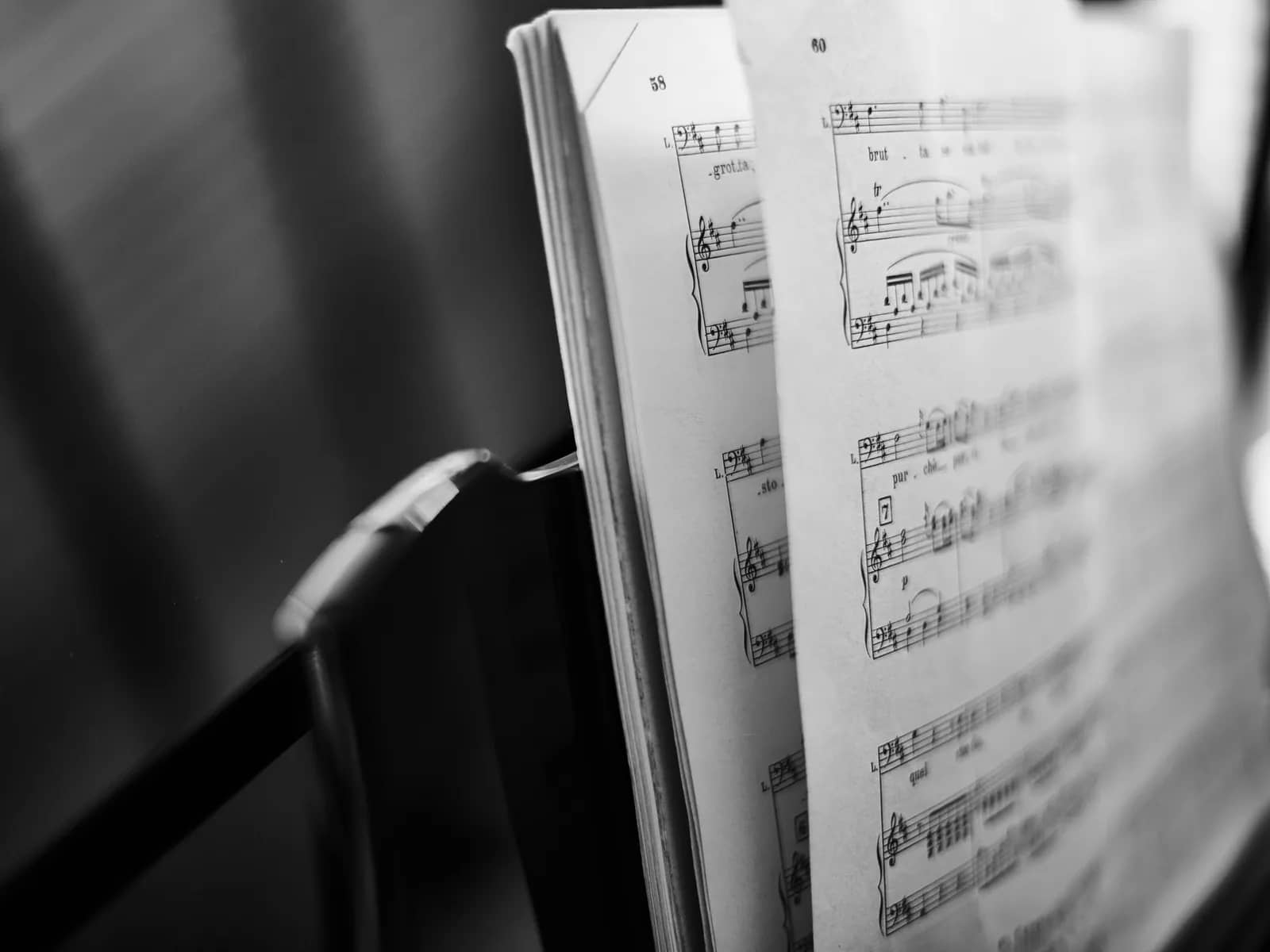 Printed vocal scores open on a black music stand, photographed side-on in black and white